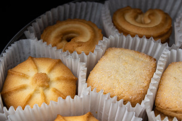 Box of sugar cookies in paper baskets in the dark