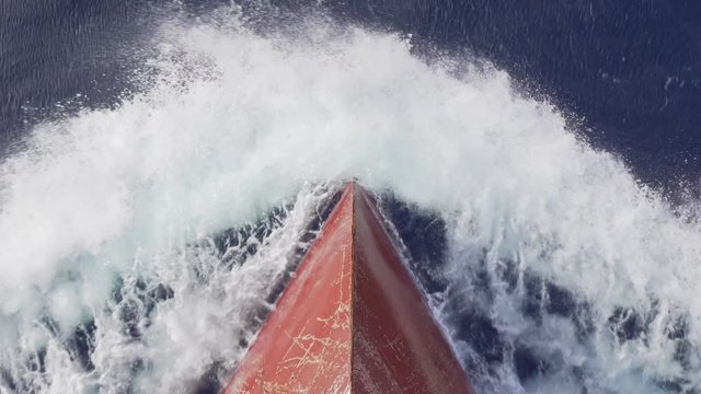 red bow bulb of a modern cargo ship crashes a wave