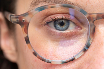 close up on young girl blue eye wearing with corrective lens glasses