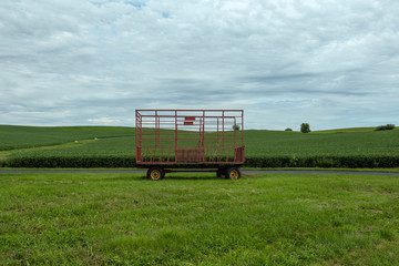 Fototapeta premium Large hay bale trailer sitting empty in vast field waiting to be used for harvest