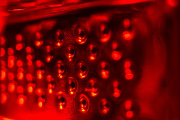 Metal surface with holes close-up in red light, abstract background.
