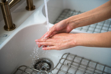 Woman washing hands in kitchen sink