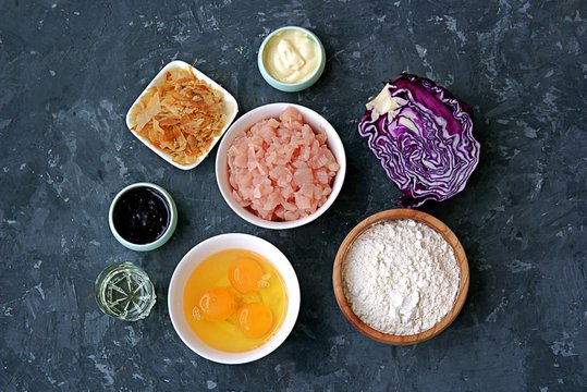 Ingredients for okonomiyaki, national Japanese dish: red cabbage, eggs, flour, mayonnaise, teriyaki sauce, sliced chicken fillet, tuna flakes, frying oil. Recipe card.