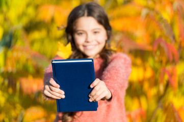 Fototapeta premium Autumn literature concept. Small child enjoy reading autumn foliage background. Little child enjoy learning in autumn park. Kid study with book. Keep studying. Small girl read book on autumn day