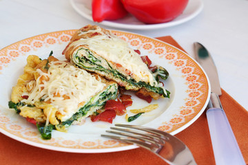 Bacon, cheese and spinach omelette on plate. Ketogenic folded omlette stuffed with low-carb high fat ingredients.