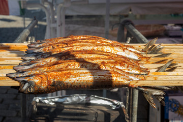 Fresh grilled mackerel fish on the wooden stick. Fish kebab. Naplavka street food market.