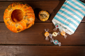Happy Halloween pumpkin and candies. Trick or treat on a wooden table on a background of old wooden boards.