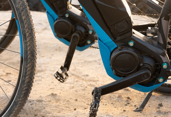 Close-up view of the battery and the motor of an electric bike. Arid footpath in a tropical place