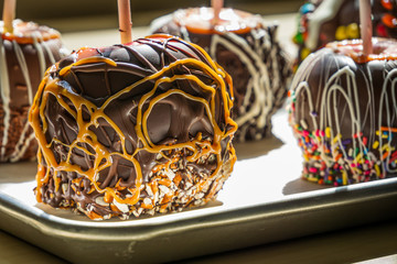 gourmet caramel apples covered in chocolate and assorted nuts and candy pieces