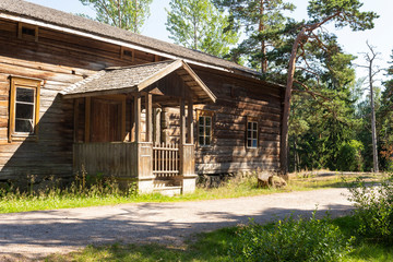 Fototapeta premium Old authentic wooden building of the 18-19th century, peasant traditional wooden hut near a road in a forest on the island of Seurasaari in Helsinki in Finland on a sunny summer day.