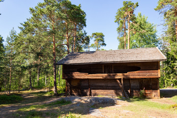 Fototapeta na wymiar A very old authentic wooden building of the 16-17th century, a peasant traditional northern wooden hut in a forest on the island of Seurasaari in Helsinki in Finland on a sunny summer day.