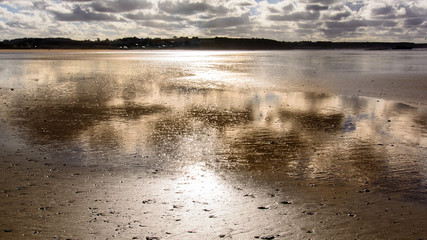 sunset on the beach and reflection on the water and sand