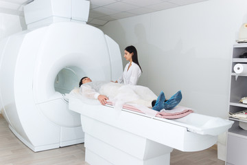 Radiologic technician and man patient lying on a CT Scan bed. preparing for MRI magnetic resonance imaging in a hospital