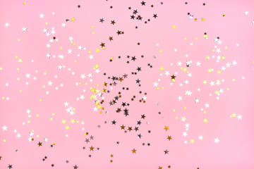 Golden and silver stars on pink pastel background. Flat lay, top view.