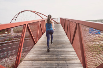 mid adult woman running on a bridge