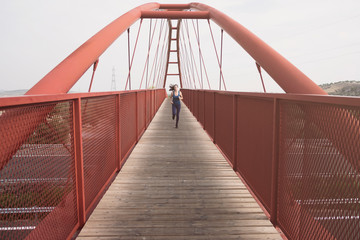 mid adult woman running on a bridge