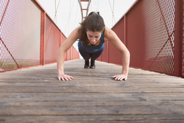 woman training push ups on a bridge