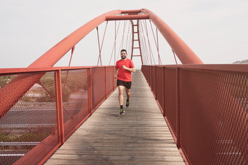 Running mid adult bearded man on bridge