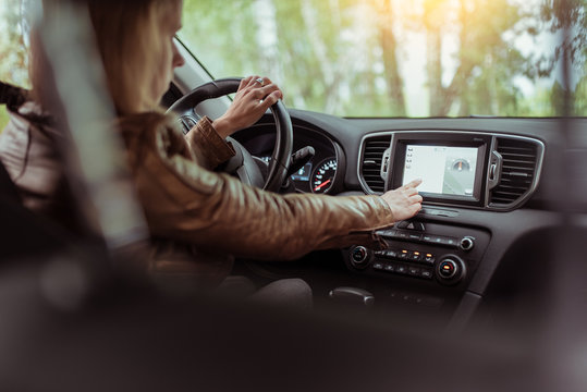 Woman girl in summer car interior in forest park, selects navigation touch screen, satellite internet application. Lost in search of a route, parking in the fresh air rest in the forest.