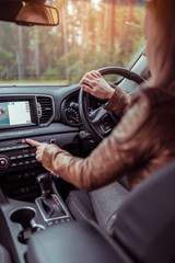 Girl woman in car interior leather jacket autumn and spring, in forest park, presses emergency stop button, switches on dimensions, accident on road, obstacle to cars signal about the accident.