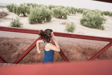 mid adult woman running on a bridge