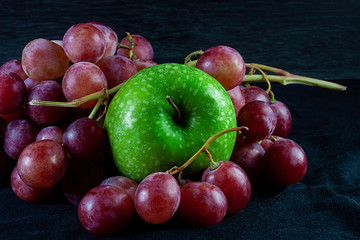 GREEN APPLE WITH GRAPE OF GRAPES ON DARK BACKGROUND. HEALTHY FOOD