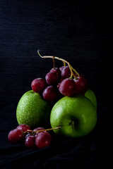 GREEN APPLE WITH GRAPE OF GRAPES ON DARK BACKGROUND. HEALTHY FOOD