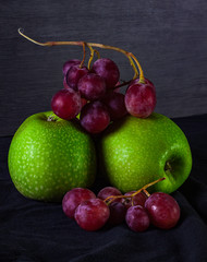 GREEN APPLE WITH GRAPE OF GRAPES ON DARK BACKGROUND. HEALTHY FOOD