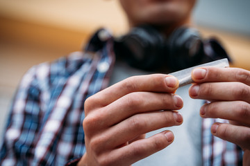 man´s hands rolling a cigarrette in rolling paper.