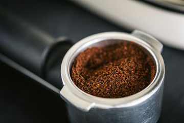 Ground black coffee in portafilter for espresso coffee machine
