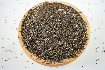 Chia seeds in a wood bowl on white background
