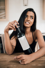 Ethnic woman showing wine bottle with white label, ideal for mockup
