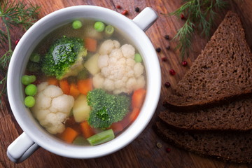 Vegetable soup in a white plate on a wooden board