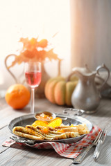 Crepes Suzette on vintage metal plate on wooden table served with orange sauce