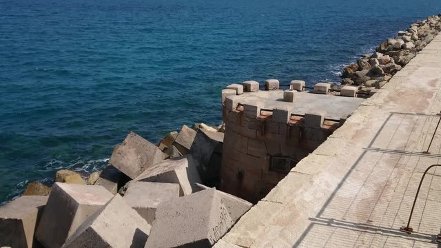Little castle at the blue sea and stones around.