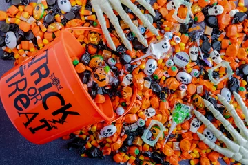 Gordijnen Halloween candy spilling out of orange trick or treat bucket © Teri