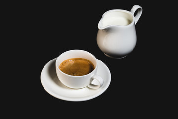 White espresso cup with coffee and milk jug on black background. Coffee cup rear view