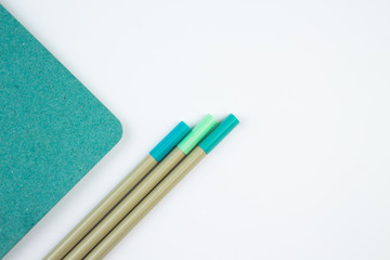 Green notebook on white surface. Close Up, copy space, top view. Minimalist concept. Colors of Year.