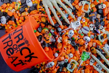 Deurstickers Halloween candy spilling out of orange trick or treat bucket © Teri