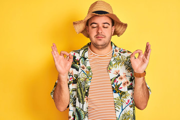 Young man on vacation wearing summer shirt and hat over isolated yellow background relax and...