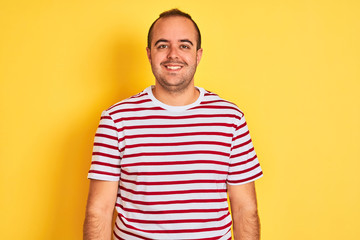 Fototapeta premium Young man wearing casual striped t-shirt standing over isolated yellow background with a happy and cool smile on face. Lucky person.
