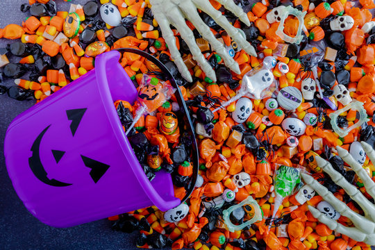 Halloween candy spilling out of purple pumpkin bucket