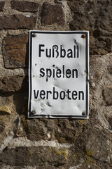 Zerbeultes Schild "Fussball spielen verboten" an der Mauer