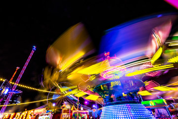 Bright colorful carosuell in neon colors in motion at a fun fair