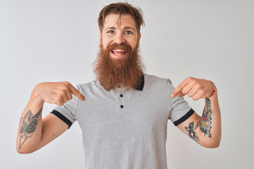 Young redhead irish man wearing grey polo standing over isolated white background looking confident...