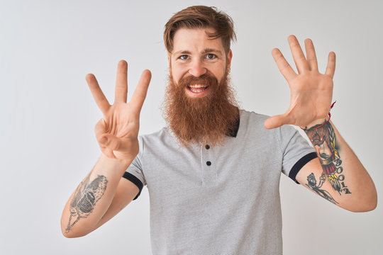 Young redhead irish man wearing grey polo standing over isolated white background showing and pointing up with fingers number eight while smiling confident and happy.