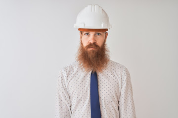 Young redhead irish architect man wearing security helmet over isolated white background Relaxed with serious expression on face. Simple and natural looking at the camera.