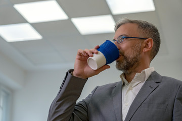 Elegant Businessman in Suit Drinking Coffee in Office