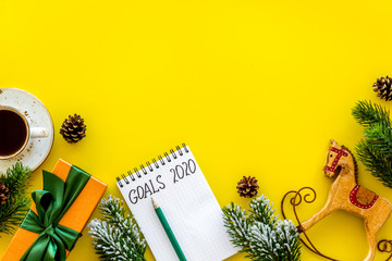 Planning New Year 2020. Notebook with goals on yellow background top view space for text