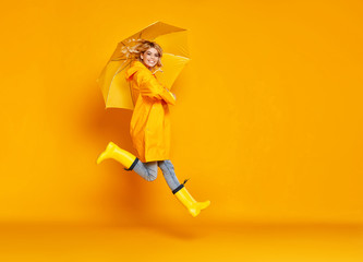 young happy emotional girl laughing  with umbrella   on colored yellow background.